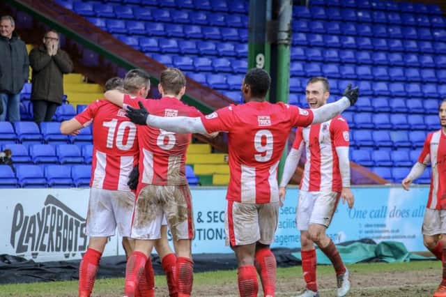 Brackley Town players congratulate Aaron Williams after his late winner at Stockport County. Photo: Will Grantham