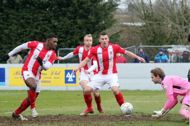 Brackley Town's Lee Ndlovu and Aaron Williams look on as Wealdstone keeper Jonathan North gets to the ball first