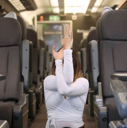 Yoga instructor Ellie Di Martino demonstrating the 'signal post' pose in the middle of a train carriage. Photo: Chiltern Railways NNL-180504-154448001