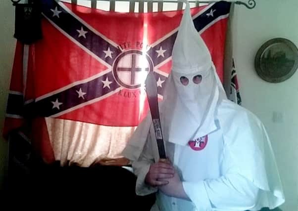 Adam Thomas alleged to be wearing a Ku Klux Klan robe in his Banbury home while holding a machete with a Confederate flag behind him. Photo: SWNS.com NNL-181029-162331001