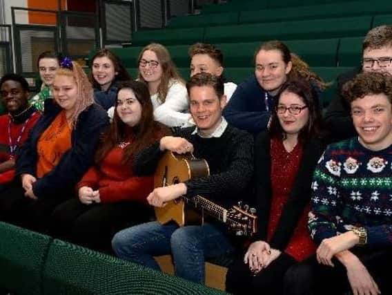 Singer songwriter Pete Gardiner (holding guitar) sits with Chenderit students before playing