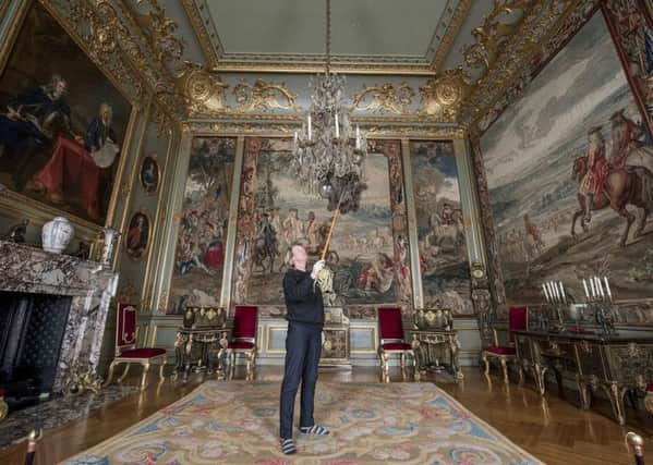 Christine Dittmers carefully cleans the chandelier in the 3rd state room in Blenheim Palace. Photographer : Mark Hemsworth