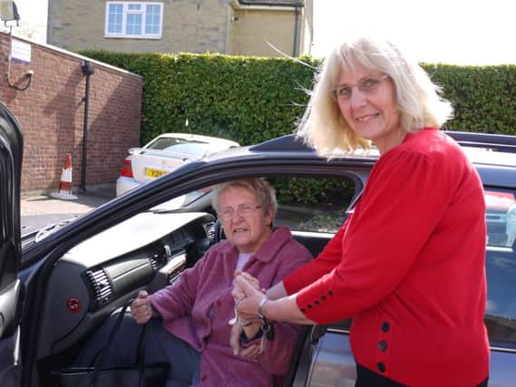 Brackley Volunteer Car Service volunteer driver Margaret Oliver helps a passenger out of her car