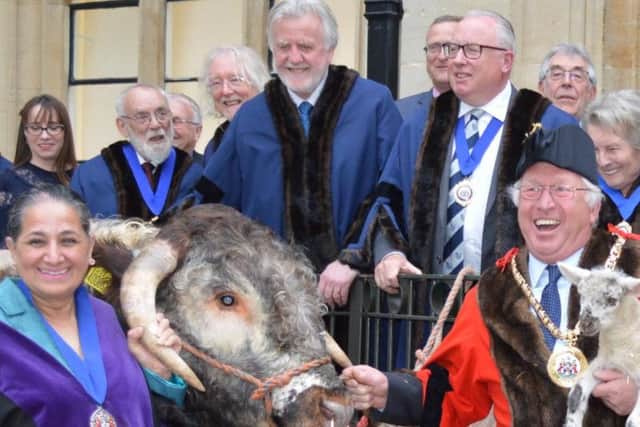 Watched by town councillors, new deputy mayor Cllr Surinder Dhesi (left) takes the bull by the horns while new mayor Cllr John Colegrave cradles one of his lambs.