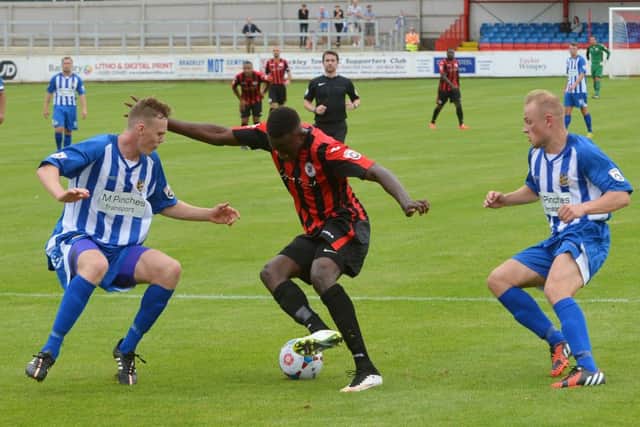 Brackley Town's David Moyo dodges between two Worcester City players at St James Park
