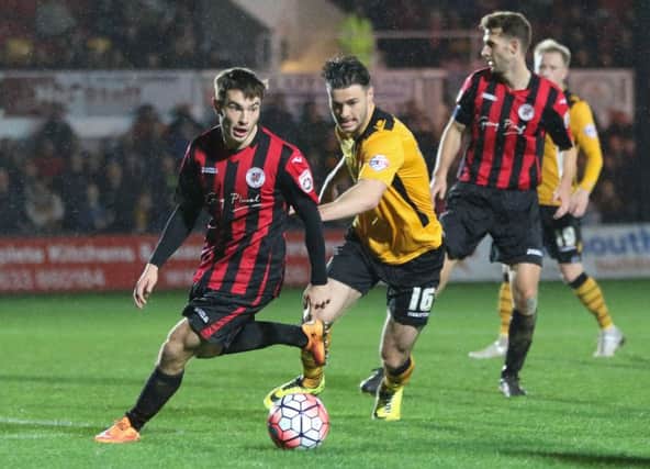 Brackley Town's Aidan Hawtin of Brackley Town is challenged by Newport County's Andrew Hughes
