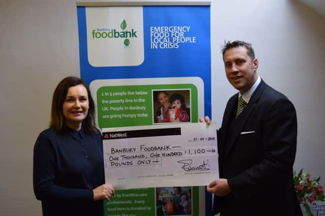 Sarah Williams of Banbury Foodbank receives a cheque from Edd Frost following their Christmas Memorial Tree display in their window of their business on Horton View. NNL-160126-092211001