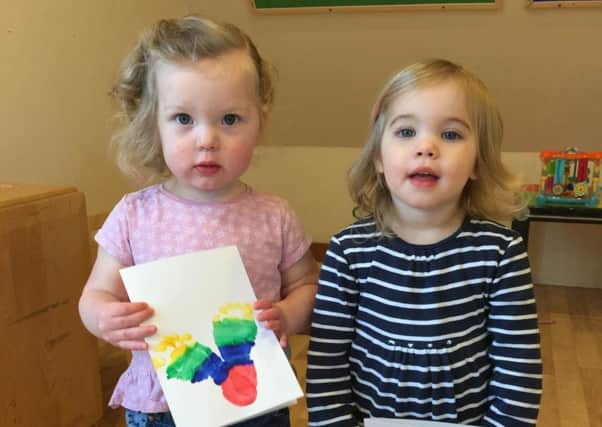 Lottie Connor and Annabelle Wassell, aged one, show off their rainbow footprint cards for their mums