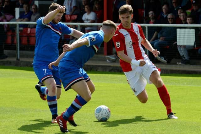 Brackley Town's James Armson takes on  FC United of Manchester's Connor McCarthy and Tom Brown