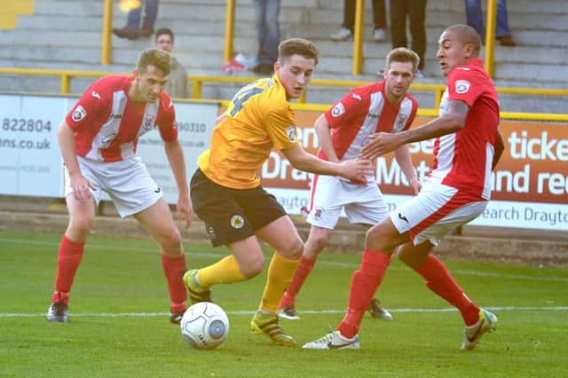 Brackley Town's Glenn Walker tries to prevent Boston United substitute Jay Rollins from getting through at York Street. Photo: David Dawson